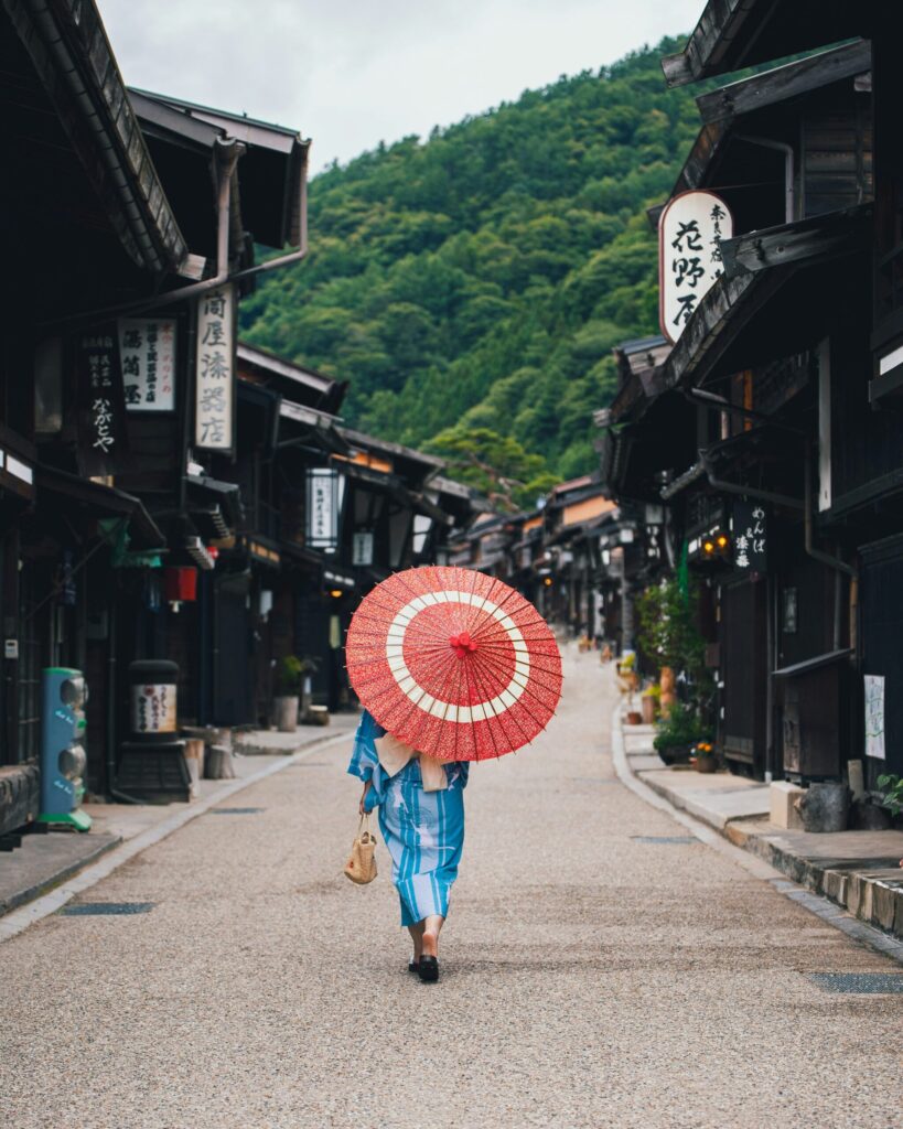 赤い傘をさした女性が歩く古い町並み。
